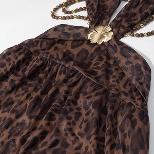 Détail d'une robe léopard avec fleur en métal doré et sangle de cou perlée
