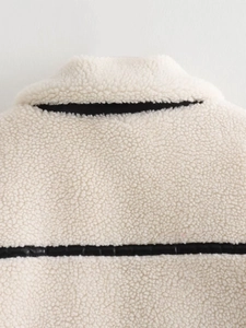 Detail of cream sherpa jacket with black faux leather contrast trim and texture