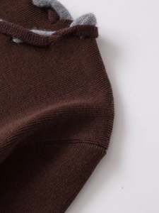 Détail du tricot marron foncé avec finitions tressées grises et texture douce de qualité