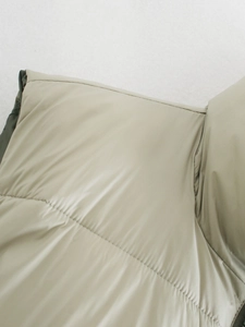 Detailed close-up of quilted beige padded vest showing fine stitching and smooth fabric texture