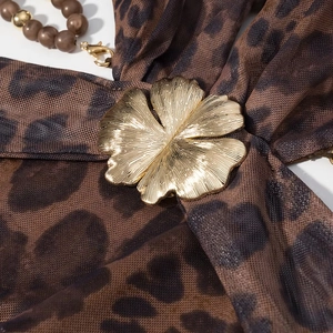 Détail du tissu en maille léopard avec fleur en métal doré et bretelle perlée chic