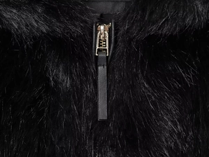 Close-up of black faux fur jacket with champagne gold metal zipper and leather puller