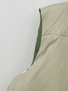 Detail of sage green quilted vest featuring matte texture and olive green lining contrast