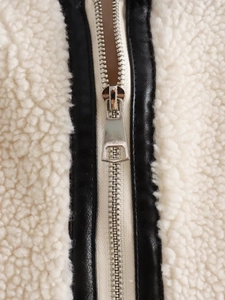 Detailed close-up of sherpa fleece and black faux leather stitching with silver zipper