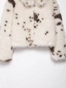 Detailed macro texture of faux fur coat featuring brownish animal spots on off-white fabric