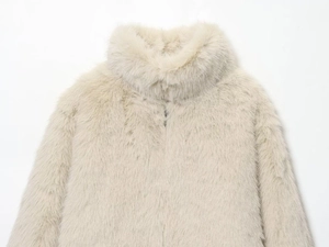 Détail du col en fausse fourrure pelucheuse sur manteau court beige clair d'hiver