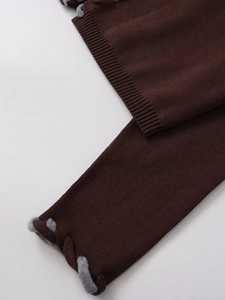 Détail d'un cardigan en maille marron foncé avec bordure en corde tressée et texture côtelée