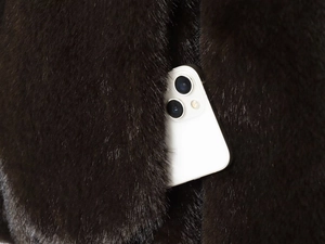 Detailansicht der Seitentasche der Kunstpelzjacke mit einem Smartphone als Größenmaß