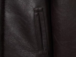 Detailed close-up showing fine grain texture and premium stitching of the leather jacket pocket