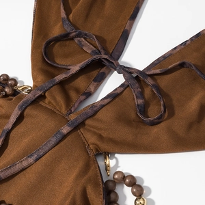 Détail de robe marron foncé avec liens léopard et perles métalliques dorées chic