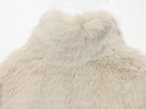 Gros plan sur la texture en fausse fourrure beige du manteau d'hiver court en peluche douce