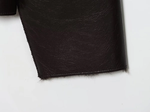 Detailed close-up of dark faux leather texture with soft fur lining and fine stitching