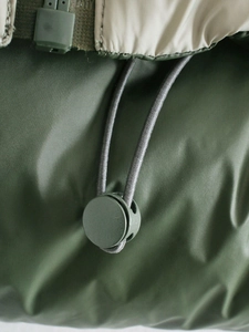 Close-up of adjustable drawstring toggle and green fabric detail on padded vest