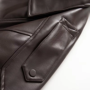 Close-up of dark brown leather jacket featuring shoulder epaulettes and matte metal buttons