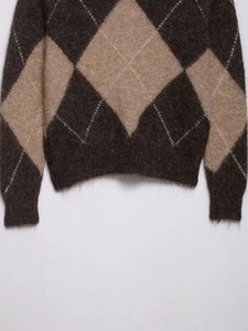 Detail of argyle knit sweater showing soft plush texture and ribbed cuffs in brown tones