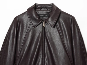 Close-up of a brown leather aviator jacket featuring textured grain and metallic zipper