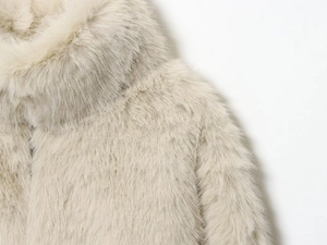 Détail rapproché de la veste en fausse fourrure crème montrant la texture douce et dense