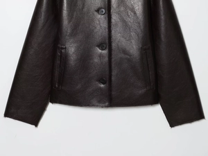 Detail of dark brown faux leather jacket featuring button closure and welt pockets