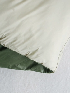 Detail of double-sided padded vest with cream white fabric and olive green lining texture