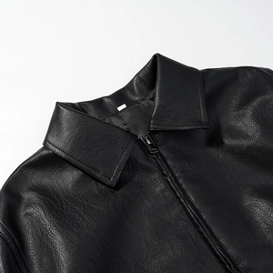 Detailed macro view of black faux leather jacket featuring lapel collar and metal zipper