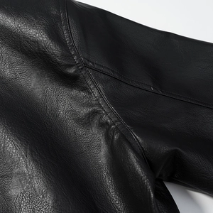 Macro detail of high-quality black faux leather jacket showing stitching on shoulder