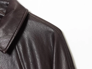 Detailed close-up of premium brown faux leather texture and fine stitching on bomber jacket