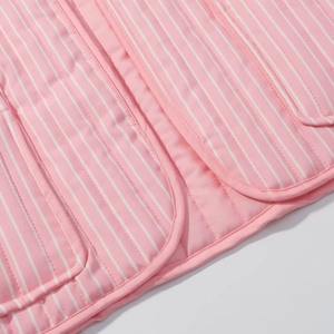 Detailed view of pink and white striped quilted cotton fabric with clean edge piping