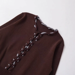 Gilet en maille marron foncé avec détails de cordons gris entrelacés et ourlet côtelé sur fond blanc