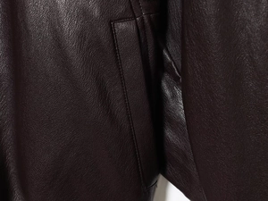Macro shot of faux leather texture and stitching detail on a burgundy bomber jacket