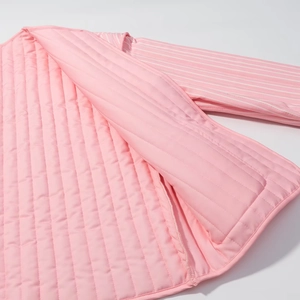 Detail view of pink quilted fabric with striped lining and vertical stitching texture
