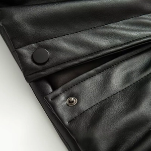 Detail of matte black metal snap buttons and double stitching on faux leather jacket