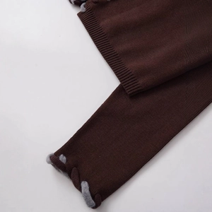 Gros plan sur un cardigan en maille marron foncé avec bordure décorative tressée grise