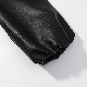 Detailed macro view showing black faux leather texture and elastic cuffs on a loose jacket