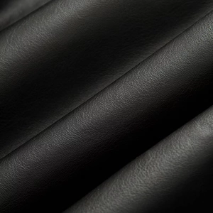 Close-up of black faux leather fabric with a premium lychee texture on bomber jacket