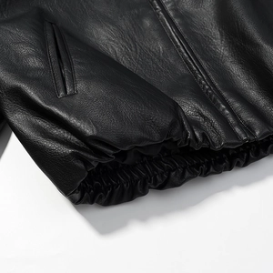 Detailed view of black leather jacket with elastic hem and textured lychee grain finish