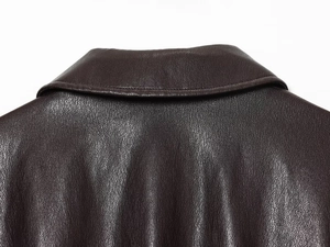 Close-up of deep brown faux leather bomber jacket showing collar and litchi texture