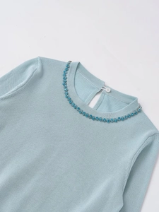 Close-up of light blue knit top featuring exquisite blue rhinestone neck embellishments