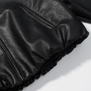 Detail view of the elastic hem and stitching on a loose black leather jacket for women