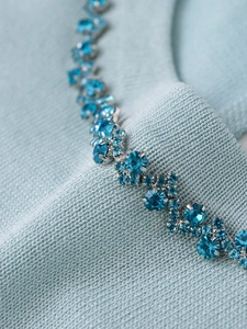 Close-up of light blue knit sweater featuring intricate sky blue rhinestone chain detailing