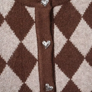 Detail of diamond pattern knit cardigan with silver heart buttons and fuzzy texture