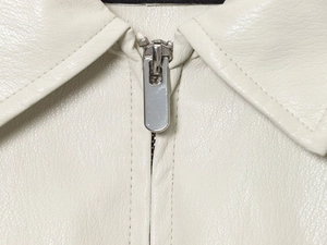 Macro shot of faux leather bomber jacket showing metal zipper and cream texture
