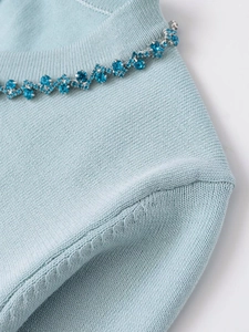 Close-up of blue beaded round neck on light blue knit sweater with crystal rhinestone detail