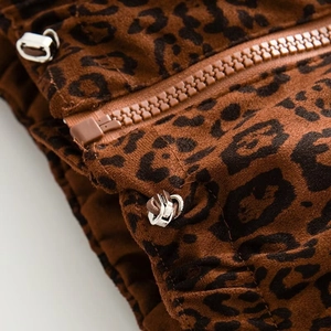 Macro detail of leopard print vest featuring a brown resin zipper and metal adjustment cord lock
