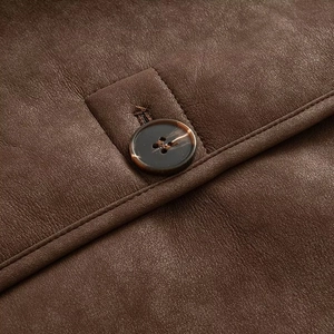 Close-up of a tortoiseshell resin button and fine stitching on a brown leather jacket