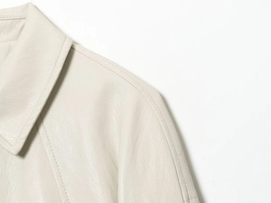 Macro shot of faux leather texture and shoulder stitching on off-white bomber jacket