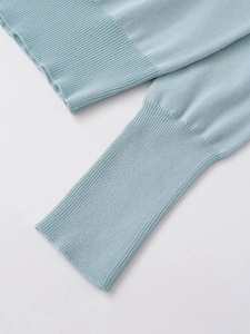 Detailed close-up of light blue knit sweater showing fine ribbed cuffs and soft texture