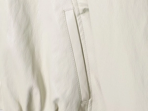 Macro detail of faux leather bomber jacket showing pocket stitching and fine texture