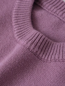 Détail du col rond côtelé sur un pull en maille violette à texture douce
