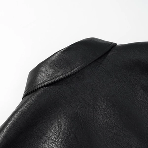 Detail shot of black faux leather jacket showing lapel collar and pebbled grain texture