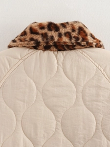 Detail of a beige quilted jacket with a stylish leopard print faux fur collar back